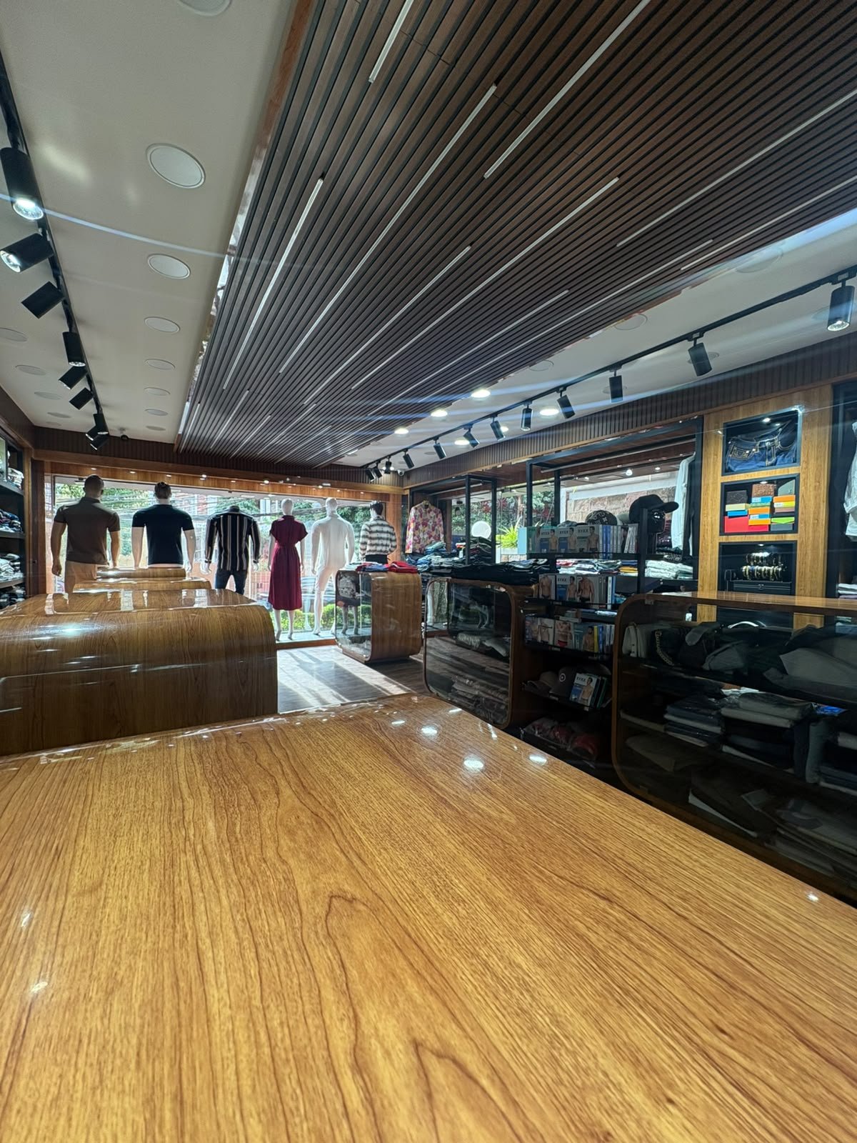 Daylight view inside Dangerous Fashion, looking across wood-panelled display counters toward the shopfront